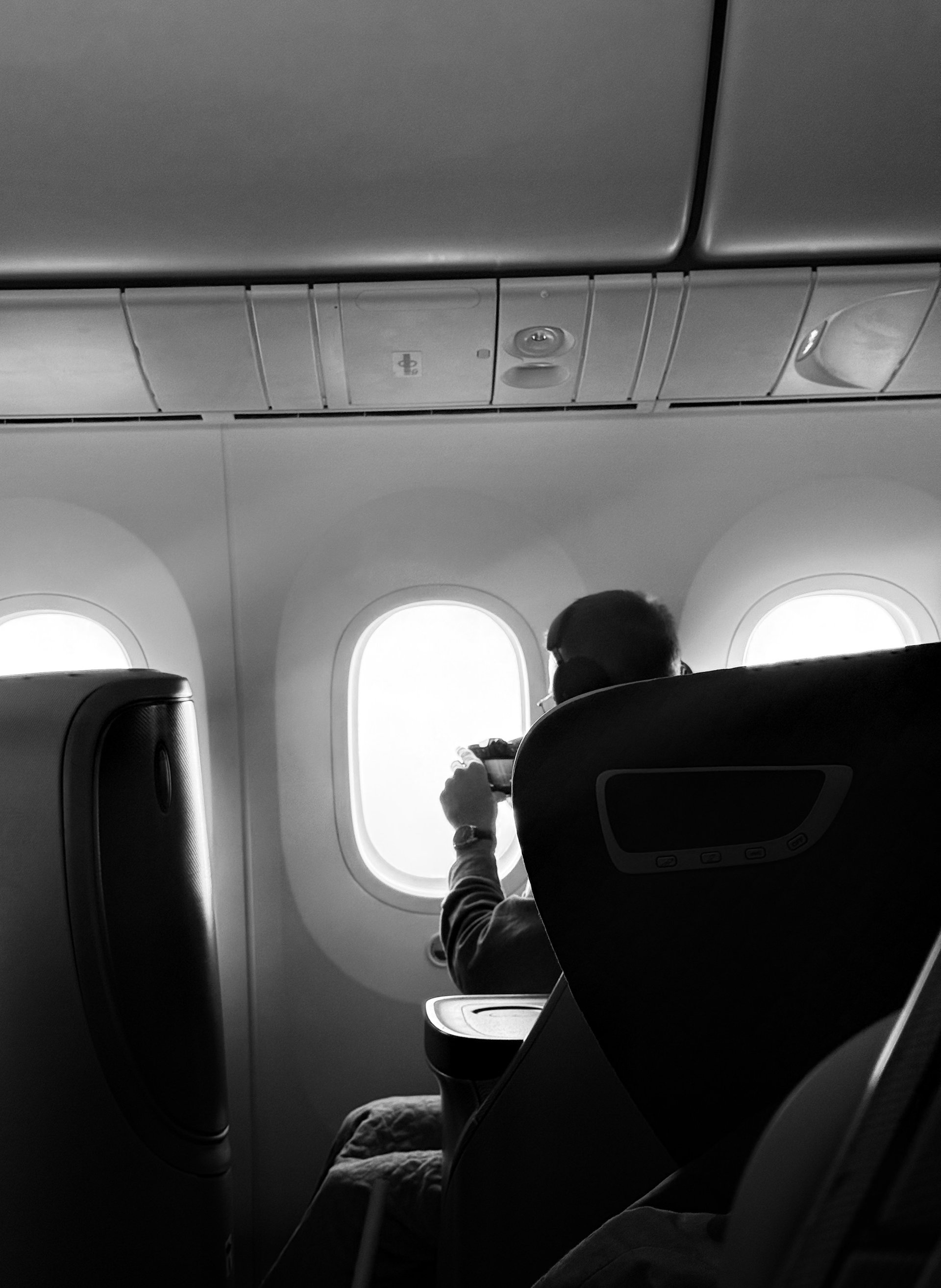 飛行機の窓から景色を撮る人